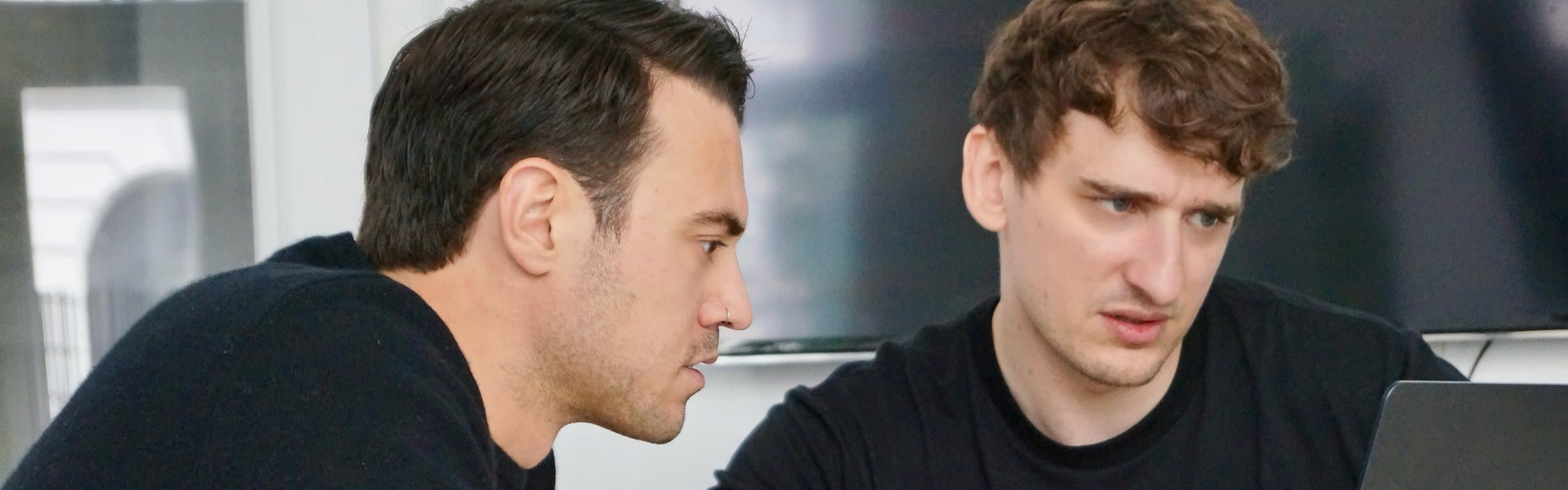 Johannes Freyer und Torben Lange sitzen nebeneinander vor einem Laptop und besprechen etwas